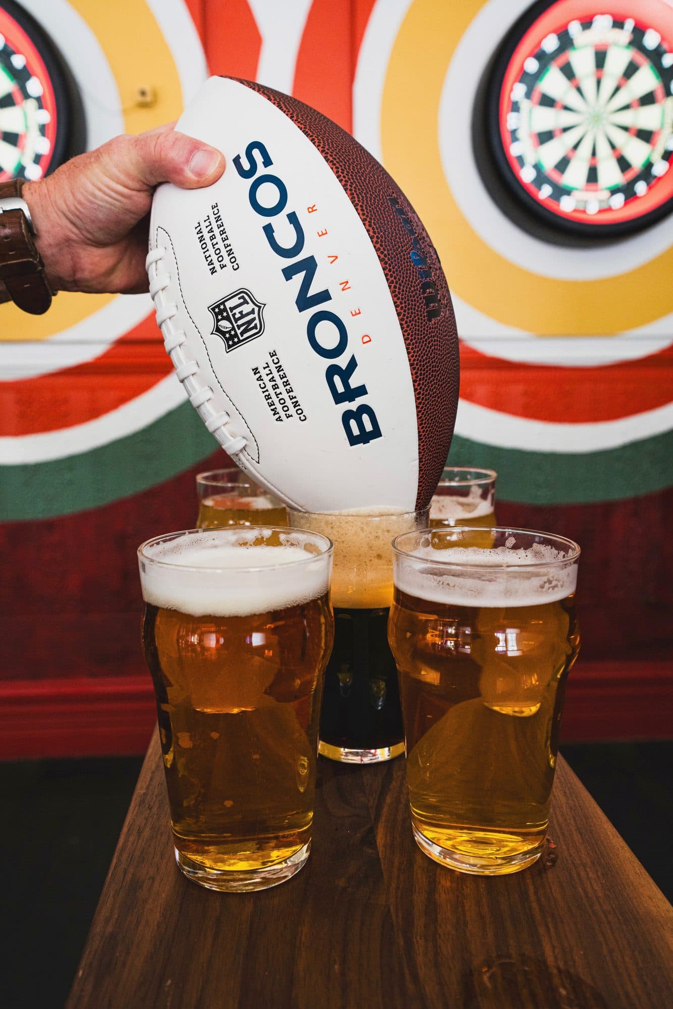 A football held over four glasses in front of the darts boards at BARna
