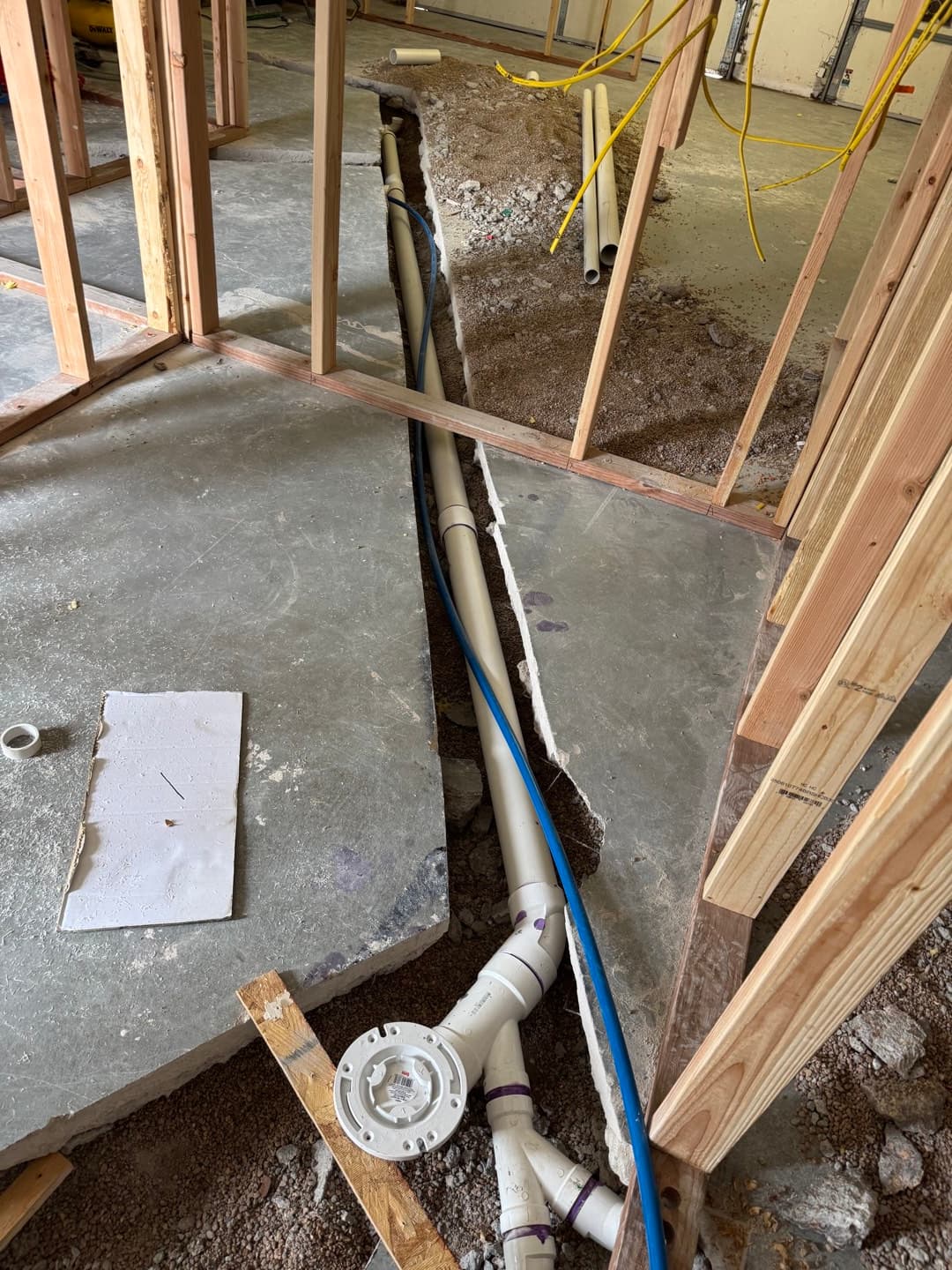 Under-slab plumbing rough-in and wall framing underway inside the ADU