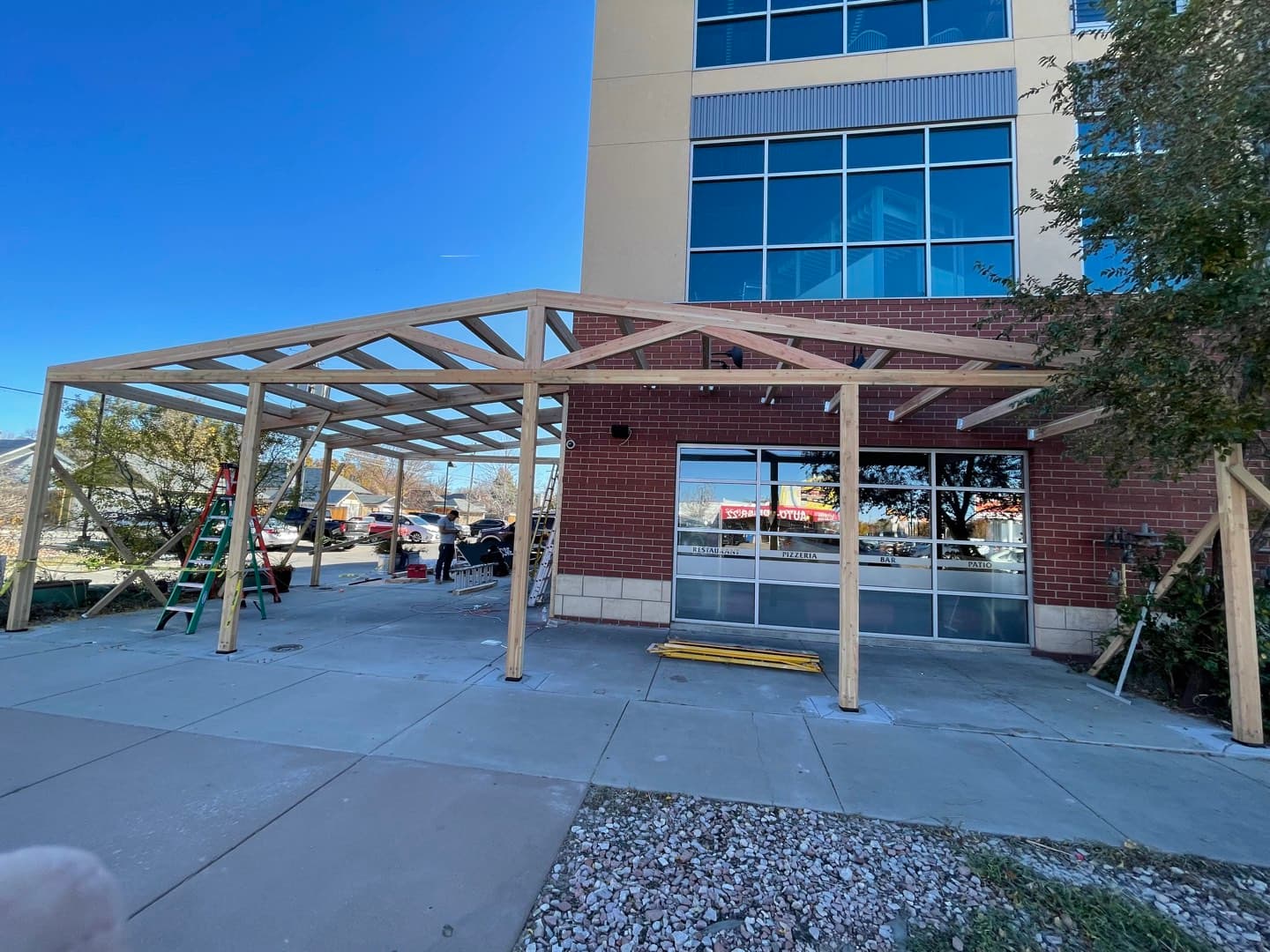 Custom timber pergola frame under construction against the restaurant’s glass front