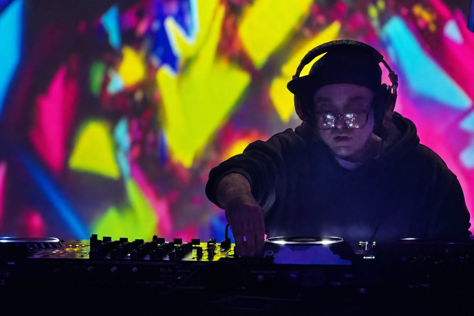 DJ mid-set with projection light across the booth